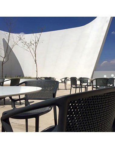 Chaise noire en plastique avec accoudoirs à une terrasse de restaurant