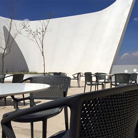 Chaise noire en plastique avec accoudoirs à une terrasse de restaurant