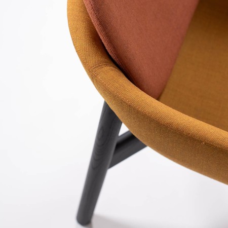 Détail du fauteuil Peb Low Back avec piètement bois teinté noir et tissu moutarde