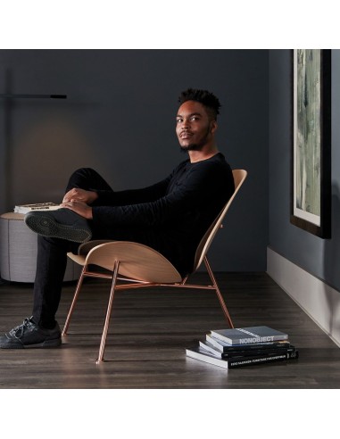 fauteuil design en bois clair et laiton antique dans un intérieur cosy et sombre