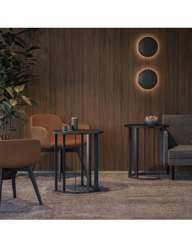 Tables basses rondes noires métal dans salon moderne avec fauteuils marron