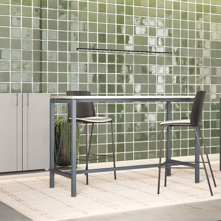Table haute NOVA avec chaises POLYTONE-L devant mur en carrelage vert