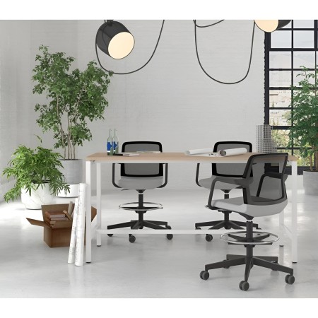 Table de réunion en bois clair avec chaises à roulettes et plantes vertes en bureau lumineux