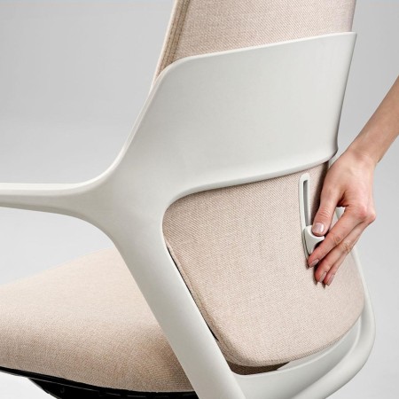 Main réglant le soutien lombaire d'une chaise de bureau, illustrant l’ergonomie personnalisable du siège.