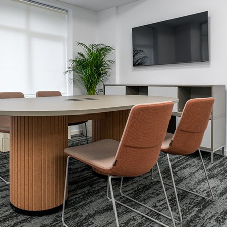 Chaises TWIST&SIT en tissu orange avec piètement luge gris autour d’une table de réunion ovale