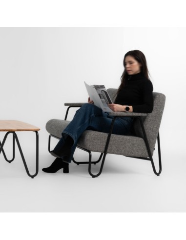 Fauteuil Clip en tissu gris avec accoudoirs bois, occupé par une personne lisant – Clip