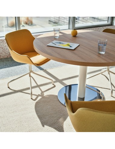 Table ronde de réunion dans pièce lumineuse et chaises design