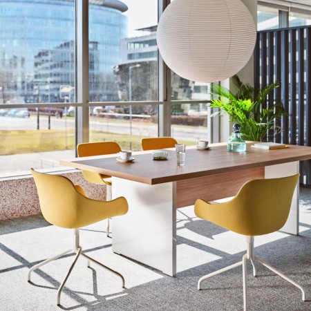 Table de réunion avec chaises jaunes et blanches dans une salle lumineuse