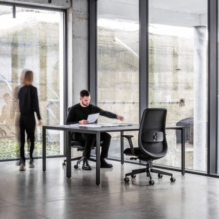 Chaise Belt BE 102 noire dans un bureau moderne avec grandes baies vitrées