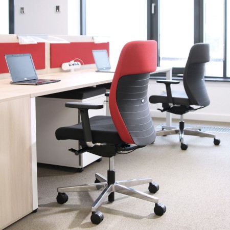 Open space lumineux avec chaises ergonomiques noires et rouges