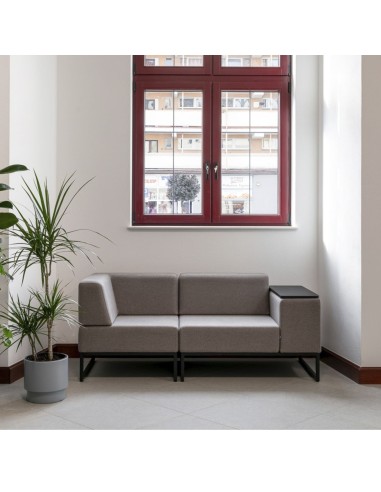 Un canapé modulaire gris clair à deux places, placé devant une fenêtre, idéal pour un espace détente lumineux. - Plint