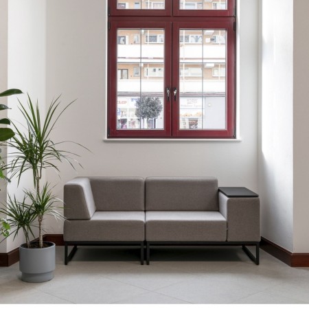 Un canapé modulaire gris clair à deux places, placé devant une fenêtre, idéal pour un espace détente lumineux. - Plint