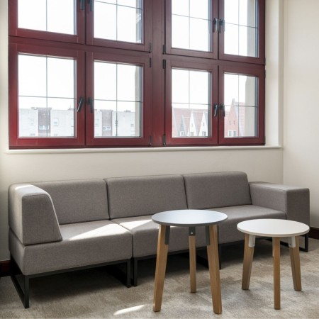 Un grand canapé modulaire gris clair positionné sous une fenêtre, offrant un espace convivial et élégant. - Plint