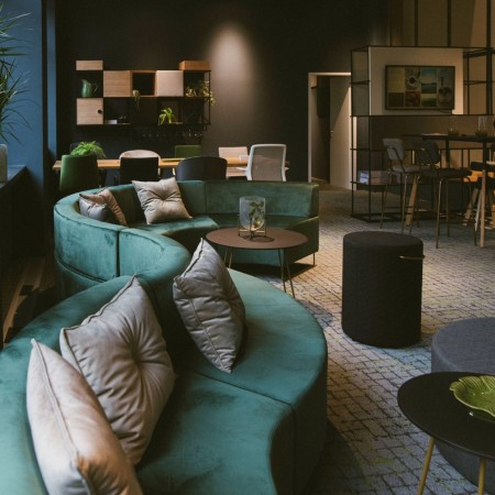 Espace détente élégant avec banquettes vertes et table en bois clair. - Quadra