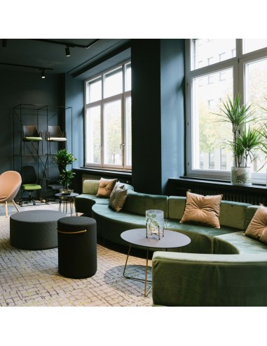 Espace lumineux avec banquettes vertes et mobilier en bois clair. - Quadra