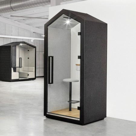 Utilisatrice debout dans la cabine Treehouse équipée d’un bureau haut. - Treehouse